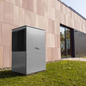 A modern heat pump unit installed outdoors next to a contemporary building, showcasing renewable energy technology.